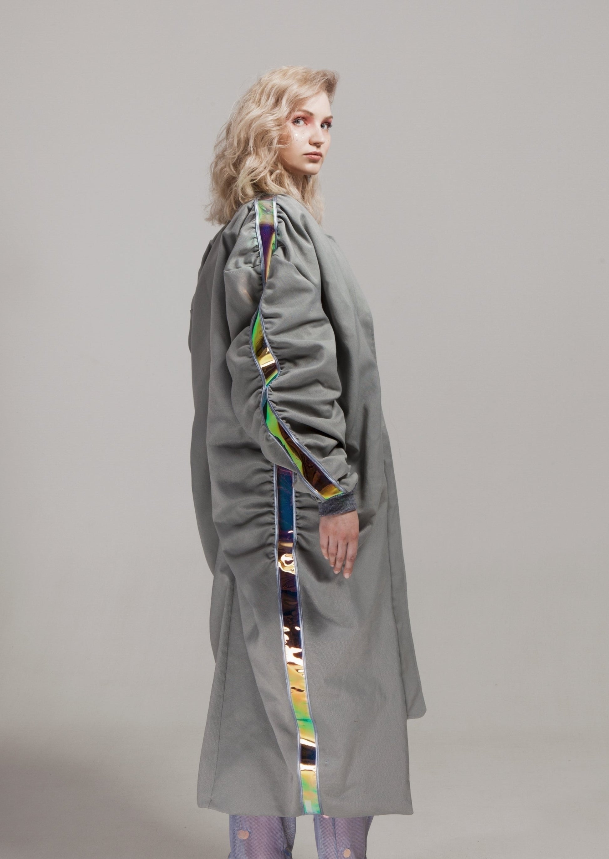 Side view of the MOON WALK coat from Cosmos Baby, highlighting the holographic PVC stripes along the side seams and the sleek, grey tech fabric